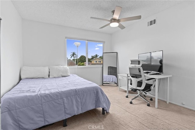 bedroom with ceiling fan, carpet, and a textured ceiling