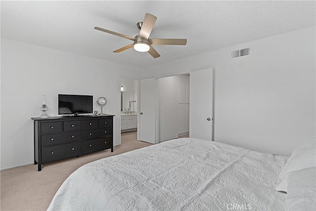 bedroom with light carpet, ensuite bath, and ceiling fan