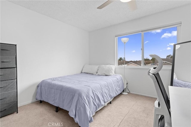 bedroom with light carpet, ceiling fan, and a textured ceiling