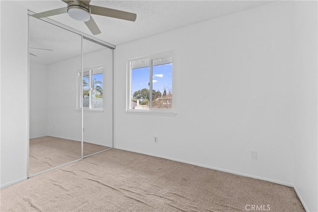 unfurnished bedroom featuring light carpet, a closet, and ceiling fan