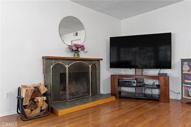 living room featuring hardwood / wood-style floors, a fireplace, and a textured ceiling