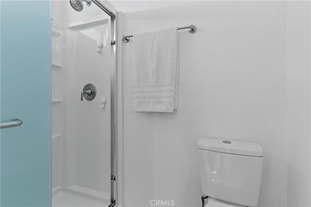 bathroom with a shower with door and toilet