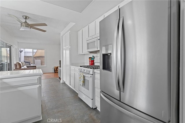 kitchen with tile countertops, white cabinetry, ceiling fan, tile patterned floors, and white appliances