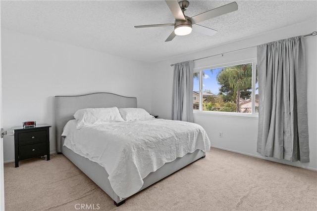 bedroom with ceiling fan, light colored carpet, and a textured ceiling