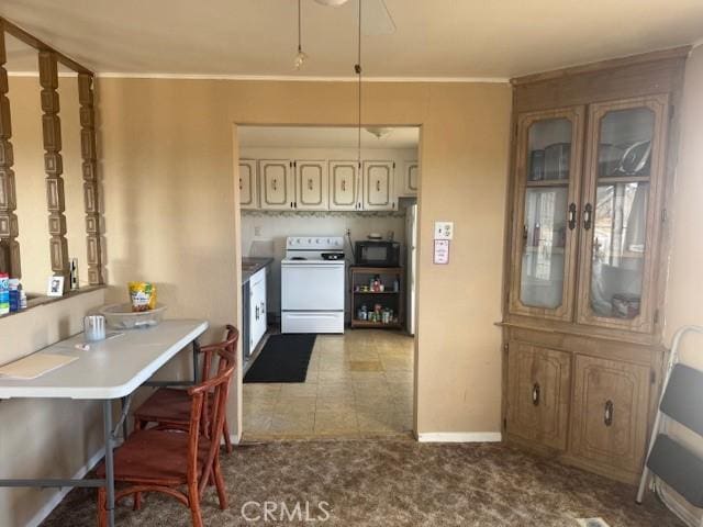 kitchen featuring ornamental molding, white electric range oven, a breakfast bar, and light carpet