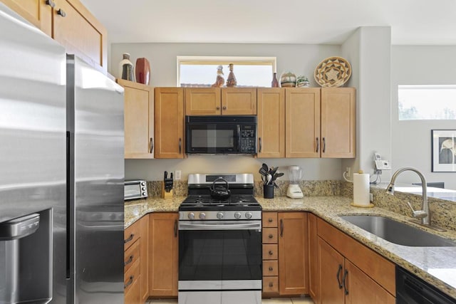 kitchen with sink, light stone counters, and black appliances