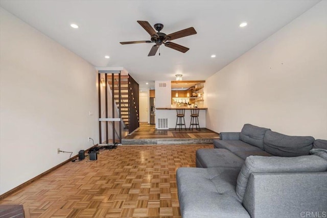 living room with light parquet flooring, indoor bar, and ceiling fan