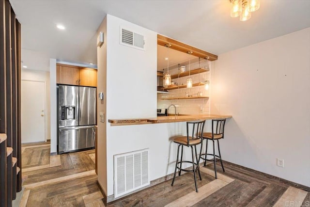 kitchen featuring stainless steel fridge, a breakfast bar, backsplash, dark parquet floors, and kitchen peninsula