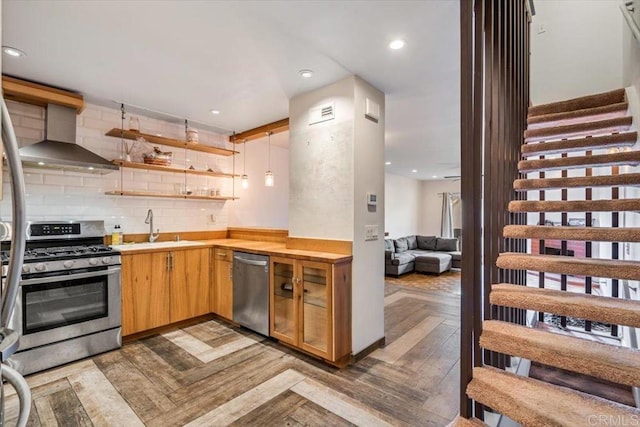 kitchen featuring tasteful backsplash, sink, dark parquet flooring, stainless steel appliances, and wall chimney range hood