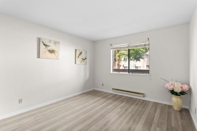 spare room with baseboard heating and light hardwood / wood-style flooring