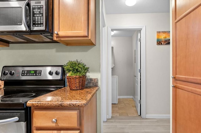 kitchen with light stone counters, washer / clothes dryer, and appliances with stainless steel finishes