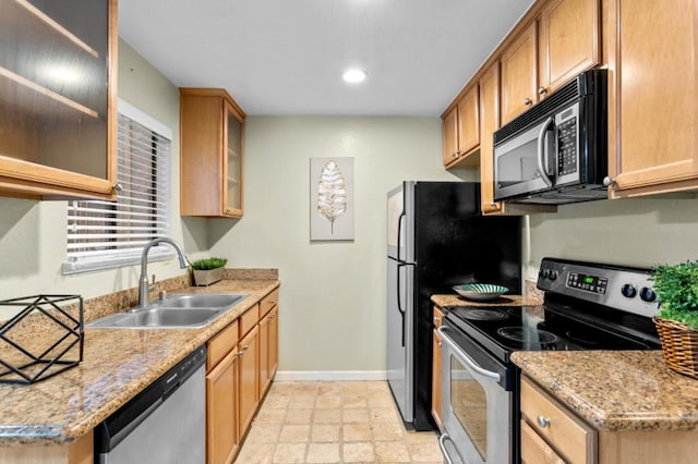 kitchen featuring light stone counters, stainless steel appliances, and sink