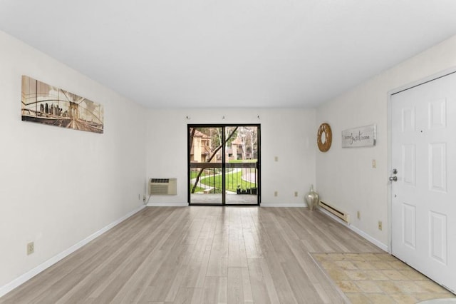 spare room with a baseboard heating unit, a wall mounted air conditioner, and light hardwood / wood-style floors