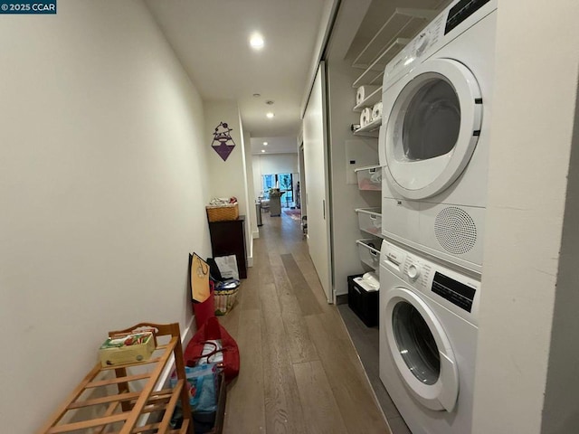 clothes washing area with stacked washer / dryer and wood-type flooring