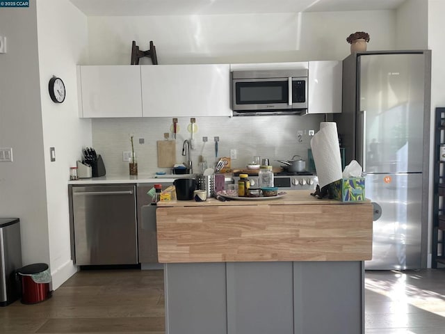 kitchen featuring appliances with stainless steel finishes, tasteful backsplash, white cabinetry, sink, and dark wood-type flooring