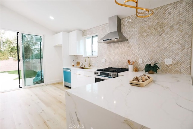 kitchen featuring sink, white cabinetry, stainless steel appliances, vaulted ceiling, and wall chimney exhaust hood