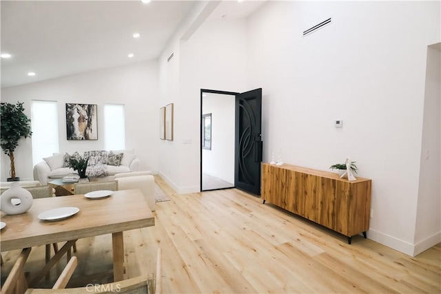 living room featuring high vaulted ceiling and light hardwood / wood-style floors