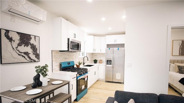 kitchen with sink, white cabinetry, an AC wall unit, stainless steel appliances, and decorative backsplash