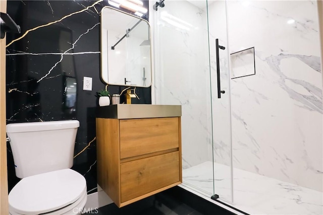 bathroom featuring vanity, a shower with door, and toilet