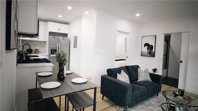 living room with sink, electric panel, and light hardwood / wood-style floors