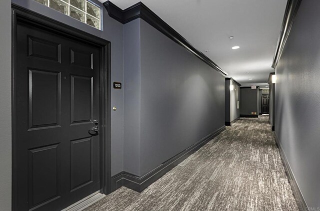 corridor with dark colored carpet, recessed lighting, baseboards, and ornamental molding