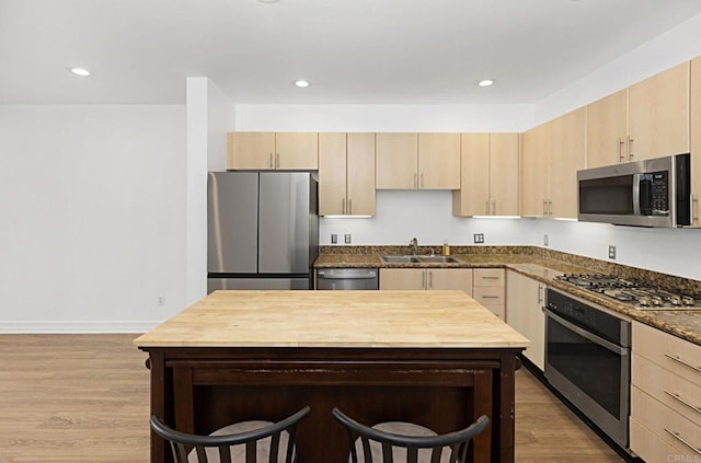 kitchen with light brown cabinets, stainless steel appliances, and a sink