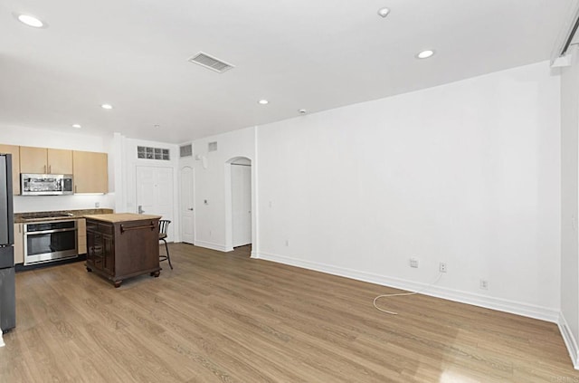 kitchen with visible vents, baseboards, arched walkways, light wood-style floors, and appliances with stainless steel finishes