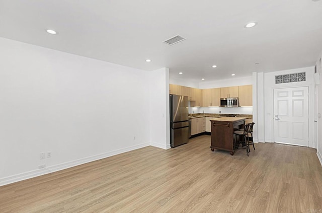 kitchen with visible vents, a kitchen breakfast bar, stainless steel appliances, light wood-style floors, and light countertops