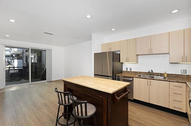 kitchen featuring a sink, light wood-style floors, appliances with stainless steel finishes, and light brown cabinetry