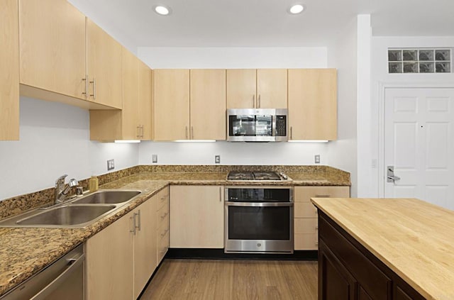 kitchen featuring a sink, light brown cabinetry, stainless steel appliances, dark wood finished floors, and recessed lighting