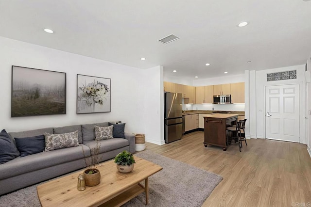 living area featuring visible vents, light wood-style flooring, and recessed lighting