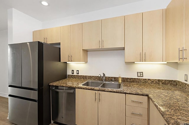 kitchen with dark stone countertops, a sink, light brown cabinetry, appliances with stainless steel finishes, and recessed lighting