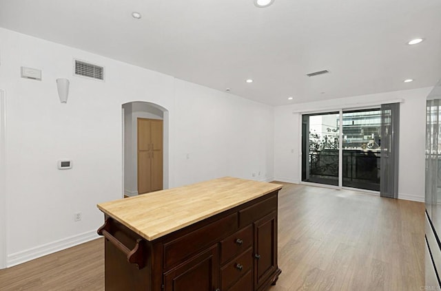 kitchen with arched walkways, baseboards, light wood finished floors, and visible vents