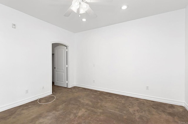 spare room with recessed lighting, ceiling fan, dark colored carpet, arched walkways, and baseboards