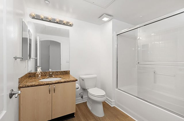full bath featuring toilet, wood finished floors, shower / bath combination with glass door, baseboards, and vanity