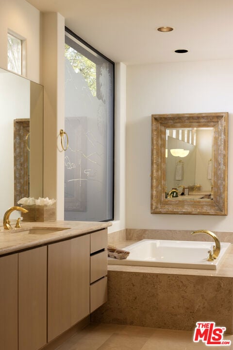 bathroom featuring vanity, a relaxing tiled tub, and tile patterned floors