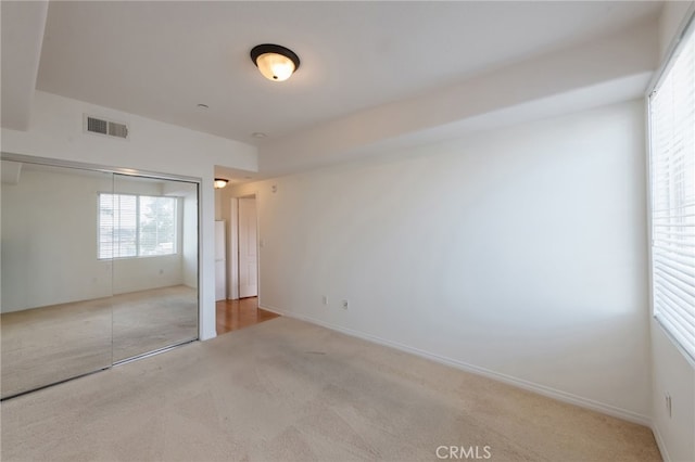 unfurnished bedroom featuring light carpet and a closet