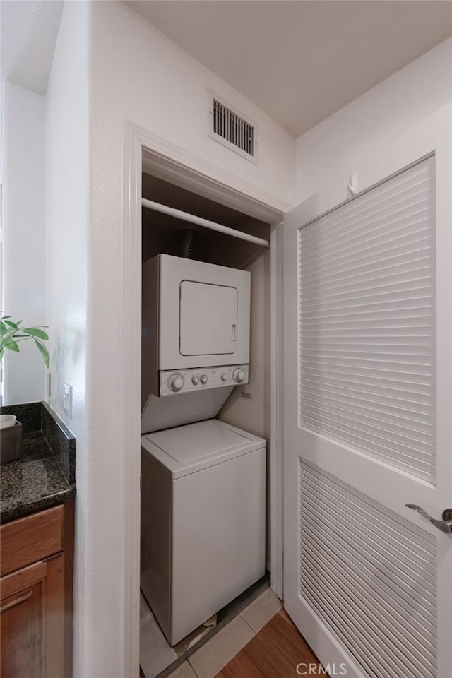 washroom with stacked washer and clothes dryer and light wood-type flooring