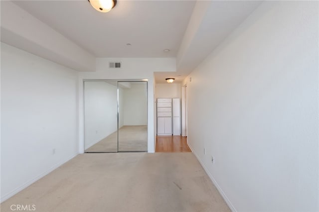 unfurnished bedroom with light colored carpet and a closet