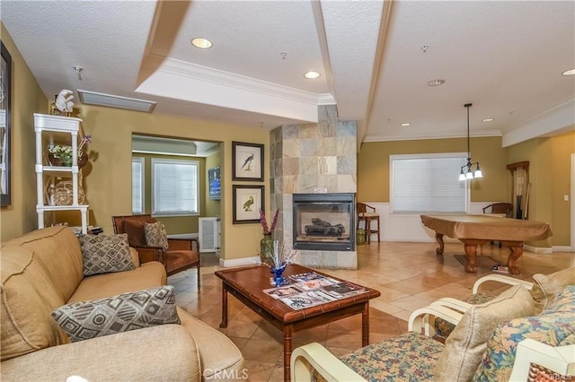 tiled living room with billiards, a tile fireplace, ornamental molding, a textured ceiling, and a raised ceiling