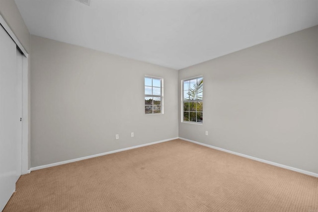 unfurnished bedroom with light colored carpet and a closet