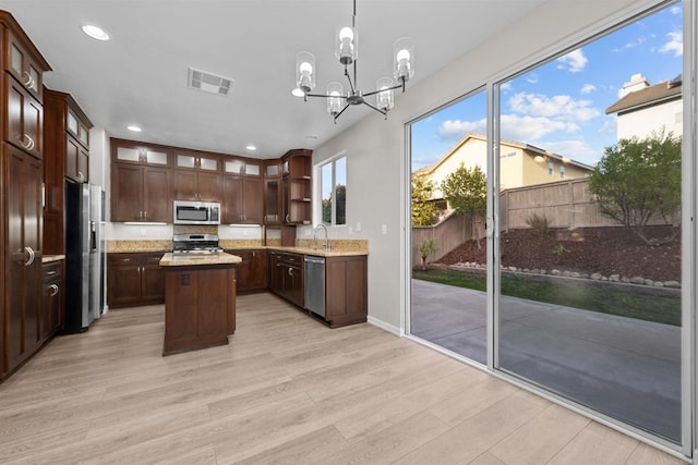 kitchen with appliances with stainless steel finishes, decorative light fixtures, sink, a center island, and dark brown cabinets