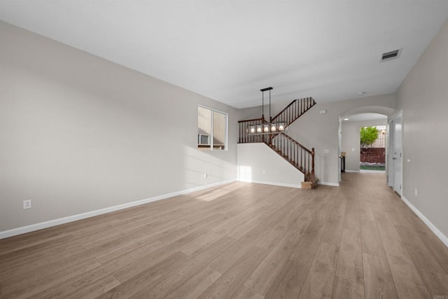 unfurnished living room with a chandelier and light hardwood / wood-style flooring