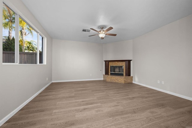 unfurnished living room with hardwood / wood-style flooring, ceiling fan, and a high end fireplace