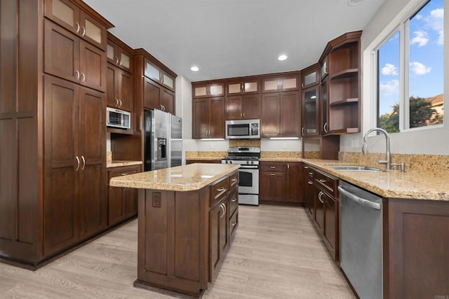 kitchen with sink, light hardwood / wood-style flooring, light stone countertops, and appliances with stainless steel finishes