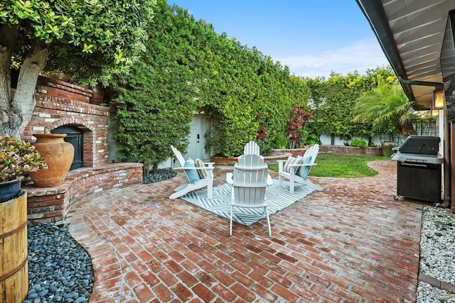 view of patio with an outdoor brick fireplace and grilling area