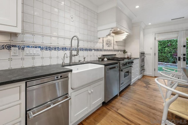 kitchen featuring stainless steel appliances, sink, white cabinets, and backsplash