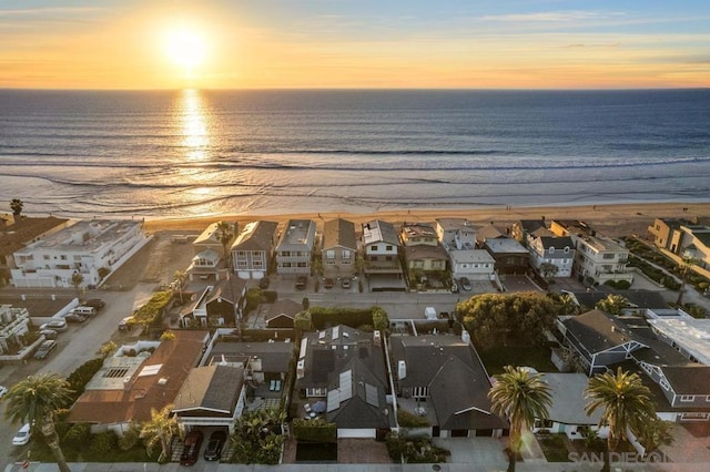 aerial view at dusk with a water view and a beach view