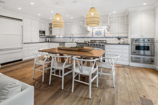 kitchen with hanging light fixtures, white cabinetry, appliances with stainless steel finishes, and sink