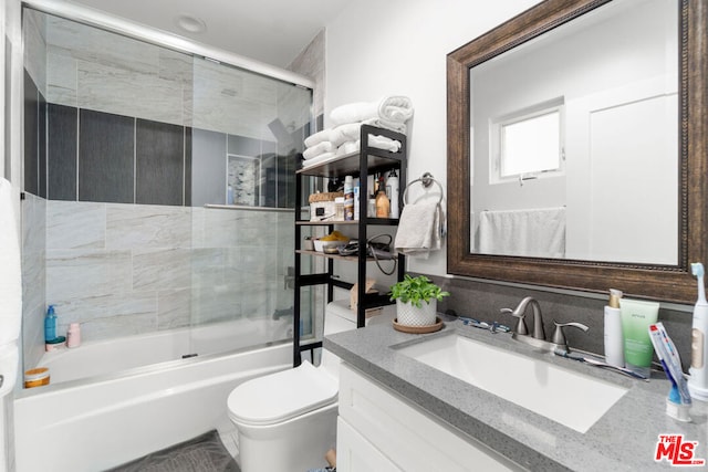 full bathroom with vanity, shower / bath combination with glass door, and toilet